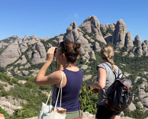 Image of hikers on a path in the Montserrat mountain, observing the solid rock mountain