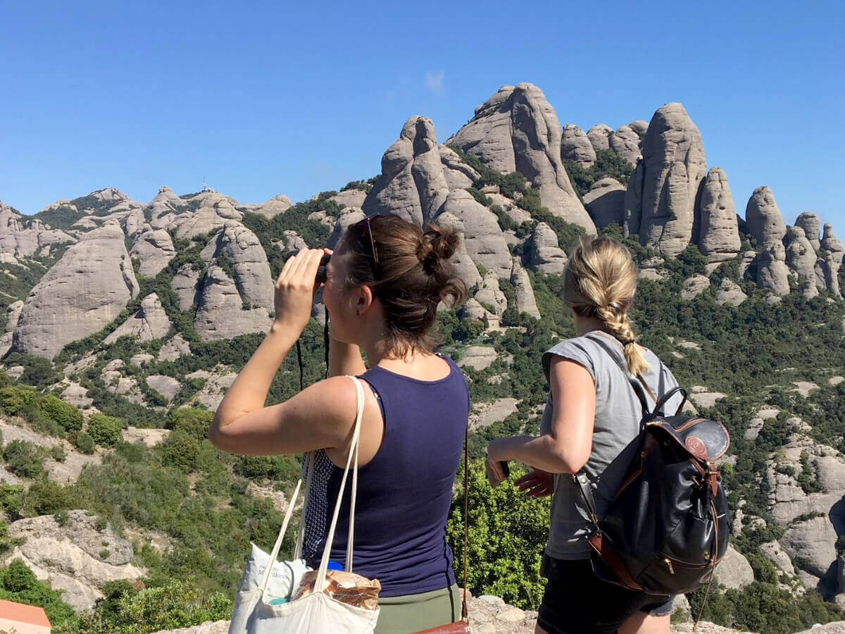 Image of hikers on a path in the Montserrat mountain, observing the solid rock mountain